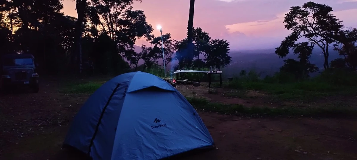 A tent pitched at dusk facing the valley